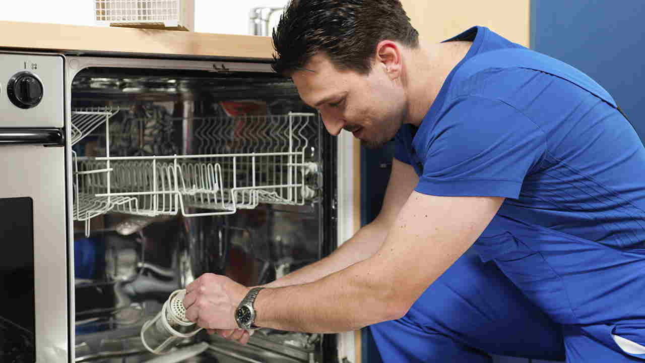 Een man repareert een vaatwasser.